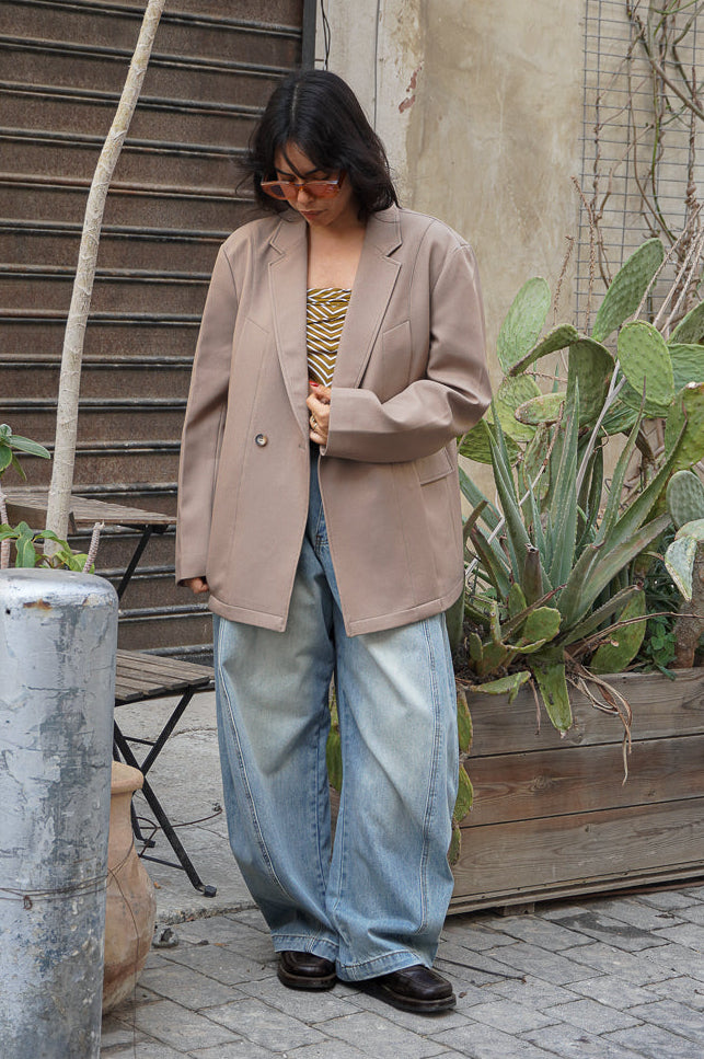 Model  wearing a beige blazer and light blue barrel jeans