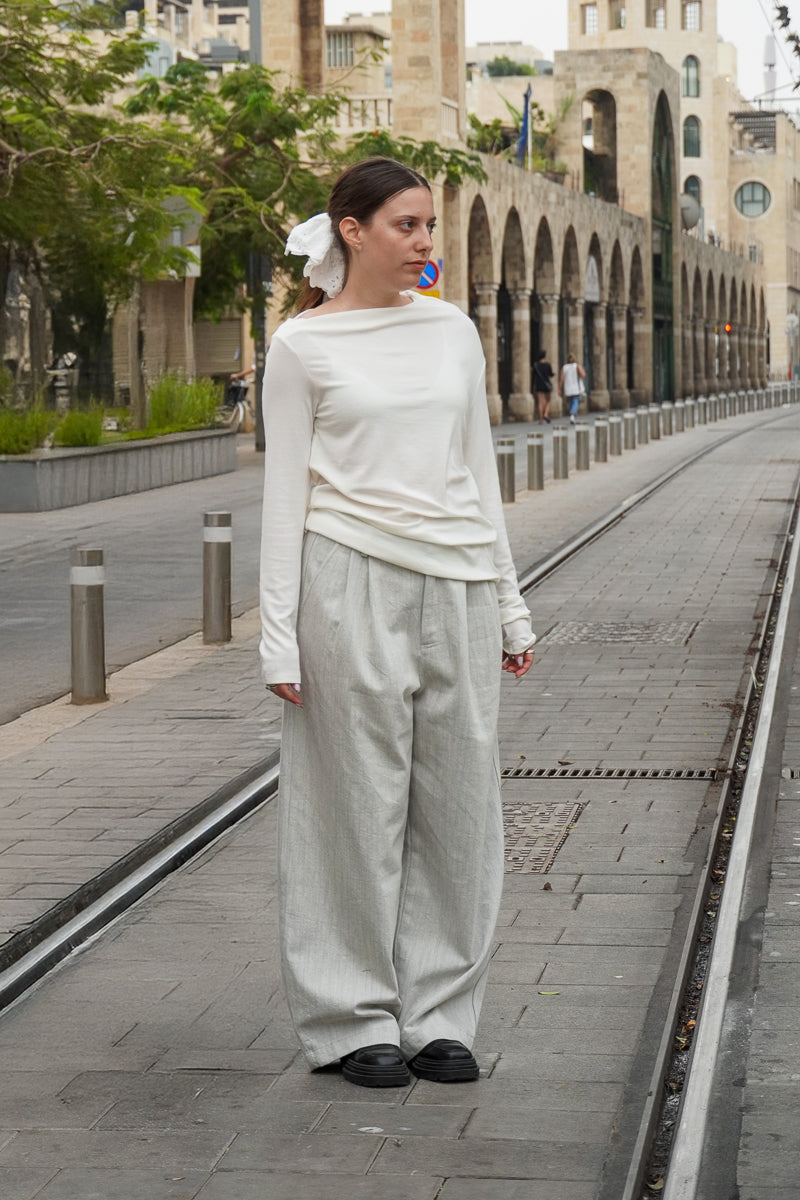 Model in a white top and light grey wide-leg tailored denim pants