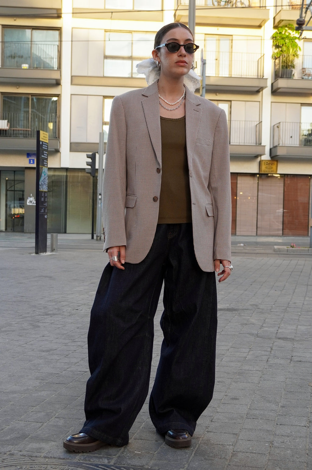 Model wearing a brown plaid blazer and dark jeans pants