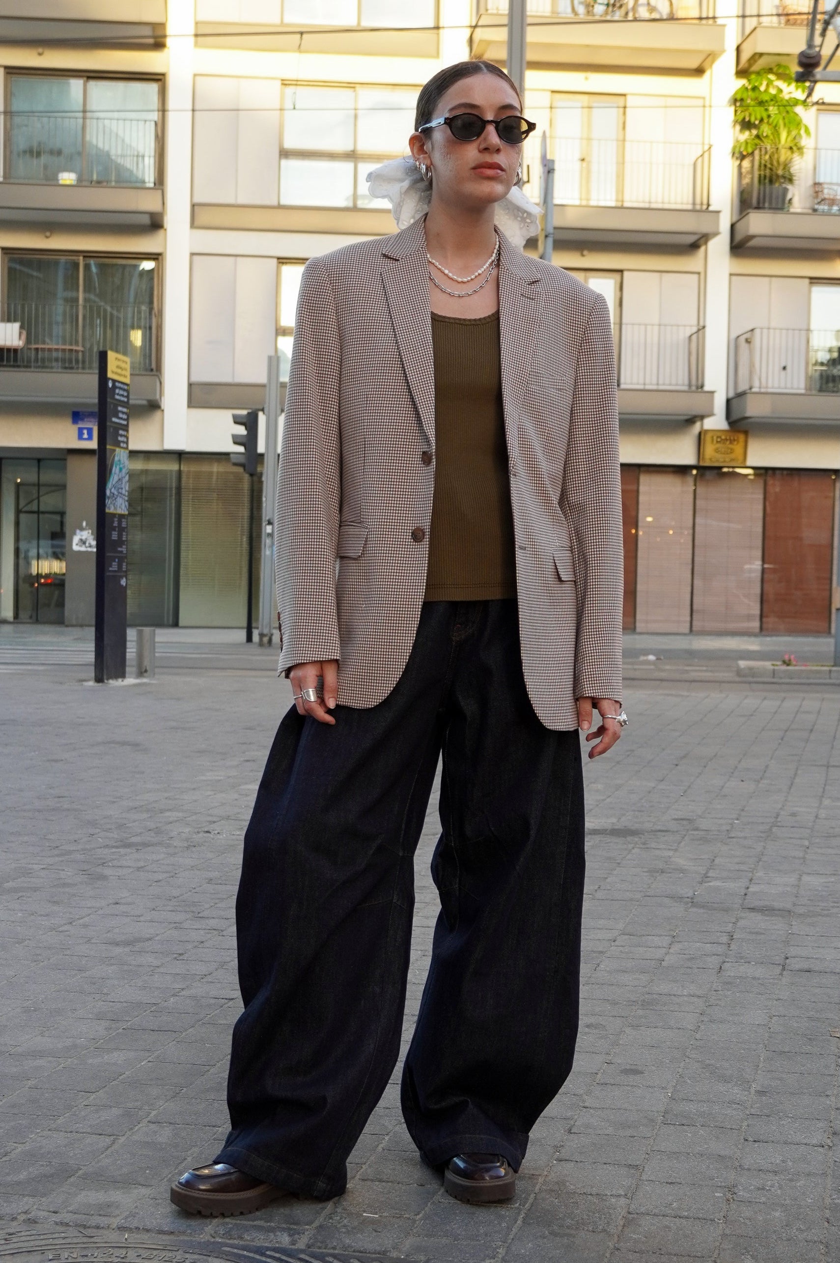 Model wearing a brown plaid blazer and dark jeans pants