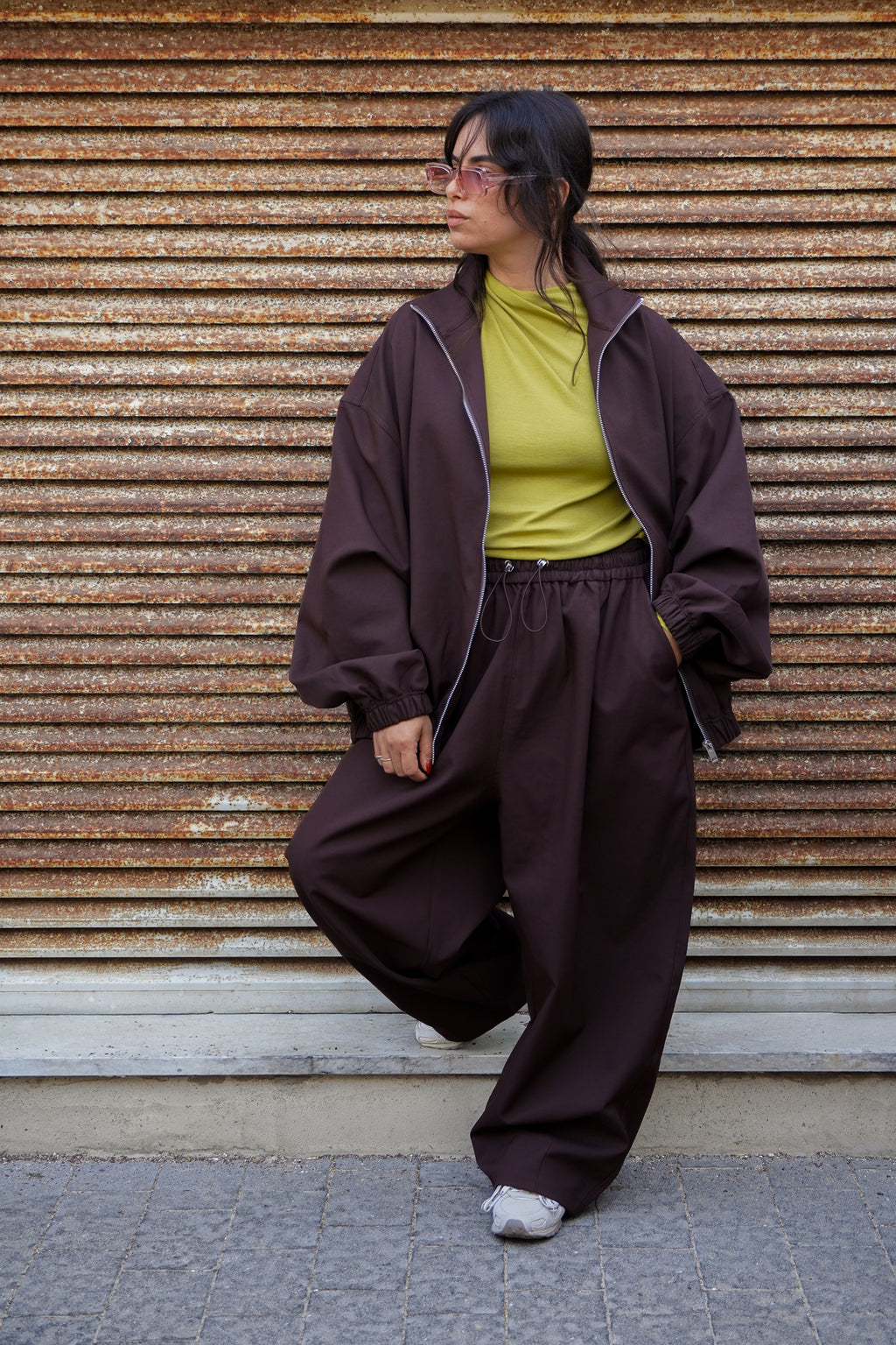 Model wearing a brown bomber jacket suit with a green shirt