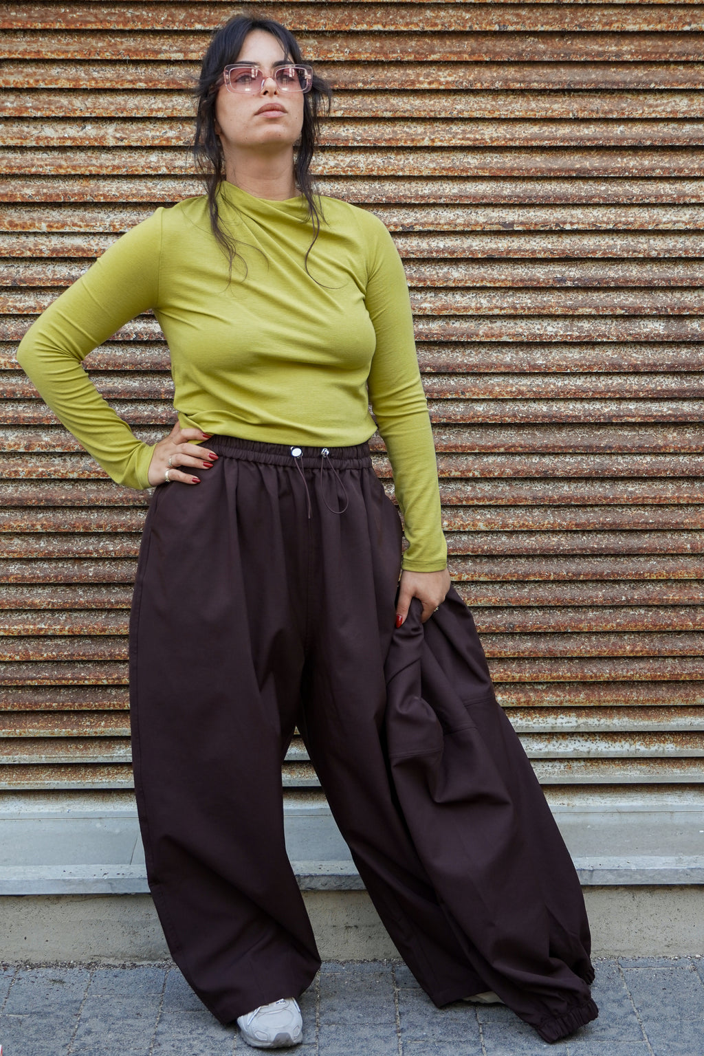 Model wearing a green top and brown wide-leg pants