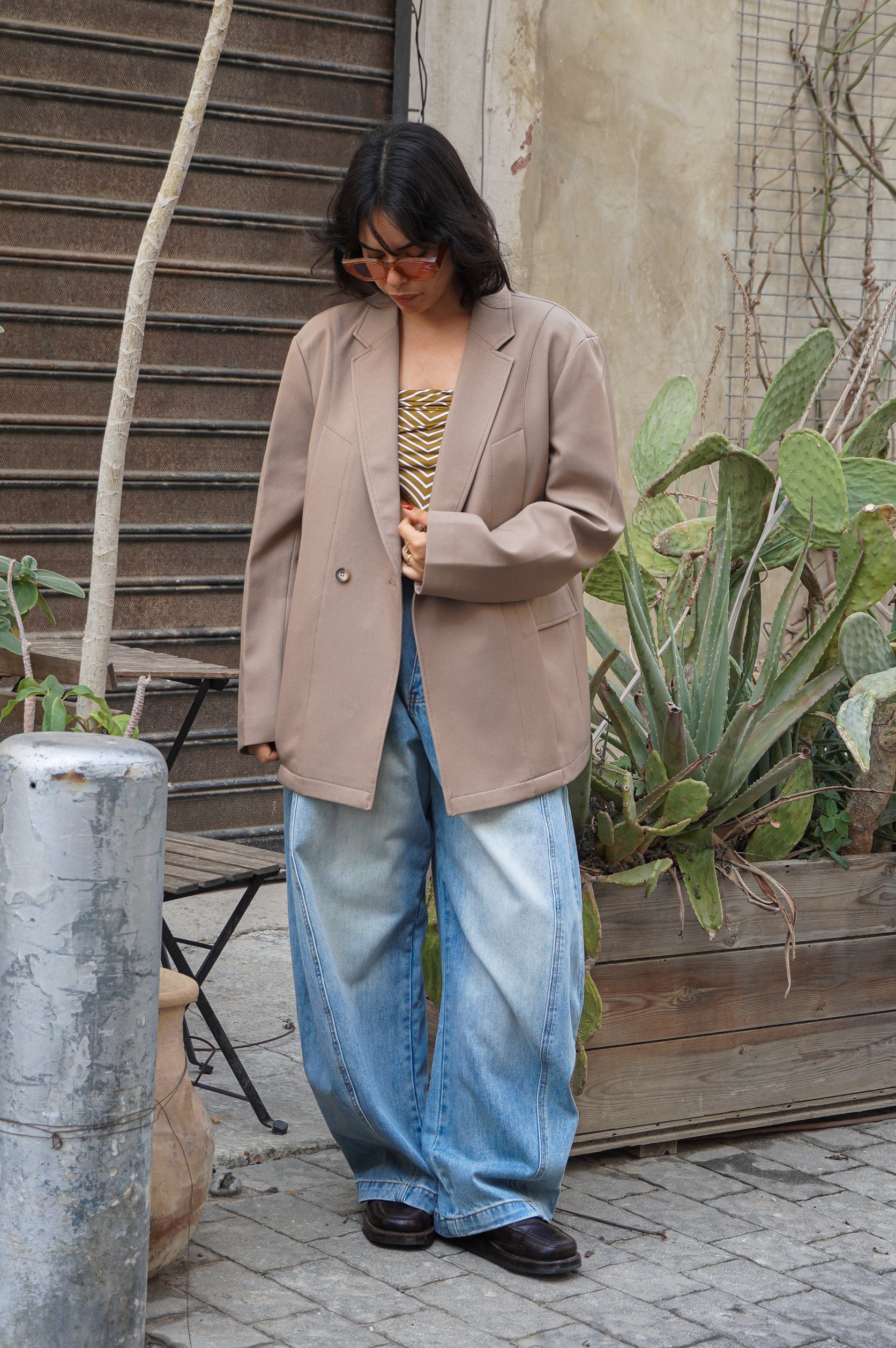 Model wearing a beige blazer and blue jeans